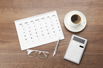 Flat lay composition with calendar and cup of coffee on wooden table