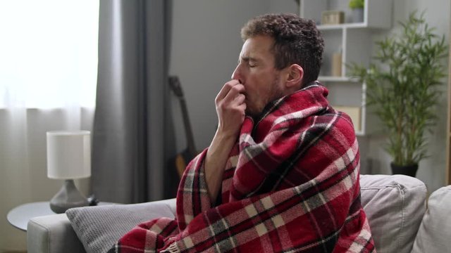 Ill man uses nasal spray on sofa in living room