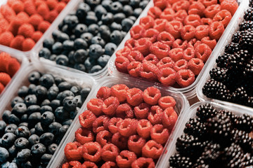 Fresh berries at display on the market stall. Blueberry, raspberry, blackberry.