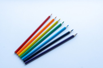 Set of seven sharp rainbow-colored pencils from top view on a white background. Concept of creativity. Art supplies. Minimalism. Childhood.