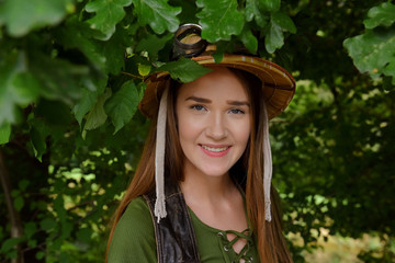 A young girl dresses up as an explorer. She wears a jungle hat and is seen in a forest environment.