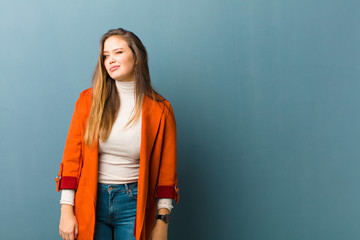 young  pretty woman looking happy and friendly, smiling and winking an eye at you with a positive...