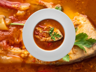Fish soup in white plate on blurred background. Overhead view.