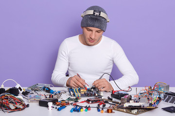 Concentrated technician repairing inside of smartphone or lap top by multimeter in lab, fixing...