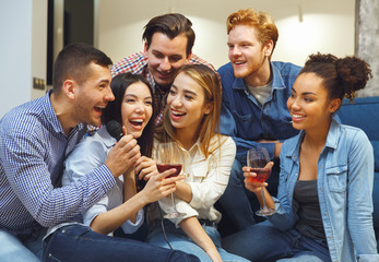 Group of friends having party indoors fun singing together