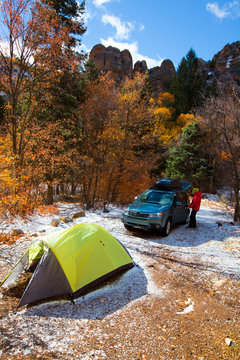 Snow mingles with fall colors as a woman sets up camp in Maple Canyon, a climbing area in Northern Utah.