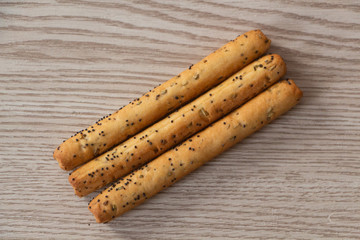 Three breadsticks with poppy seeds on wooden background