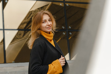 Beautiful portrait of a young girl in a yellow sweater. Woman on the street