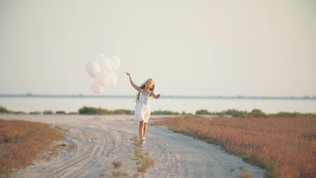 girl with balloons on a dirt road