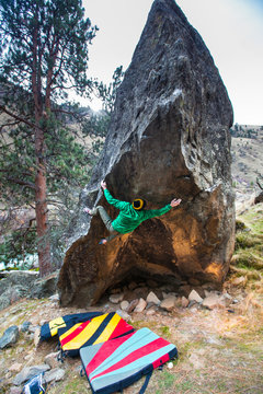 A man works on a V10-ish project that involves a hard start variation that finishes on Blazing Arrows on the Tepee Boulder along the Salmon River near Riggins, Idaho.
