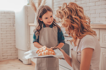 daughter and mother holding tray with croissants on the kitchen
