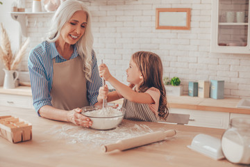 grandmother and granddaughter preparing dough for cookies