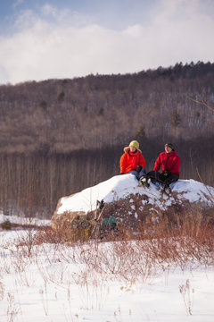 A man and woman take a break and rest on a boulder while snowshoeing in the newly-aquired 1,300 acre parcel of land at the south end of the Green Hills Preserve. The addition expanded the overall uninterrupted acreage of the preserve to 5,500 acres and as an important watershed and drainage basin for the Saco River is an important habitat for deer, black bear, moose, bobcat, fisher, brook trout, mink, beavers and  more. Portions of the acreage are undergoing revegetation and restoration of native plant species.