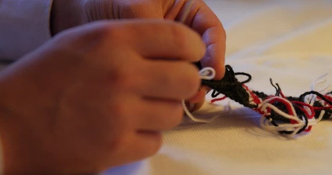close shot of man sewing with wool thread, traditional hand work