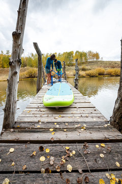 A man and a woman prepare their inflatable stand up paddle boards for SUPing in an alpine lake in the San Juan Mountains, Colorado in autumn.