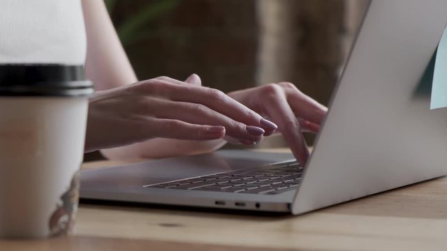 Woman working on laptop at home interier. Near the window. Hands and fingers on the keyboard close-up