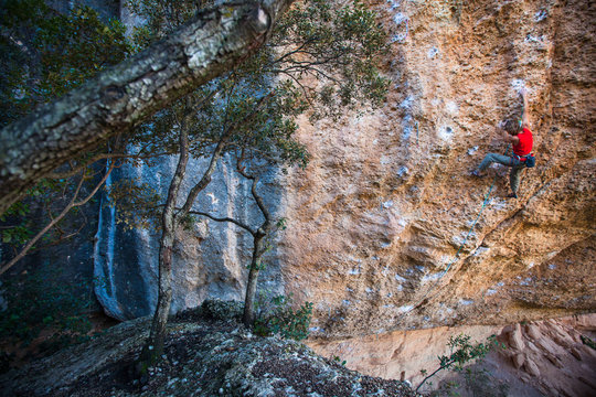 A man on La corva de la felicitat (7c) at the Raco de les Tenebres sector at Margalef, Spain.