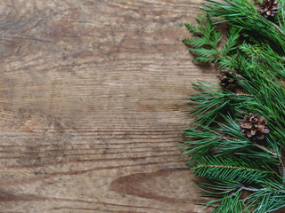 Wooden background with fir tree and pine tree branches and cones. Christmas or New Year holiday background with copy space.