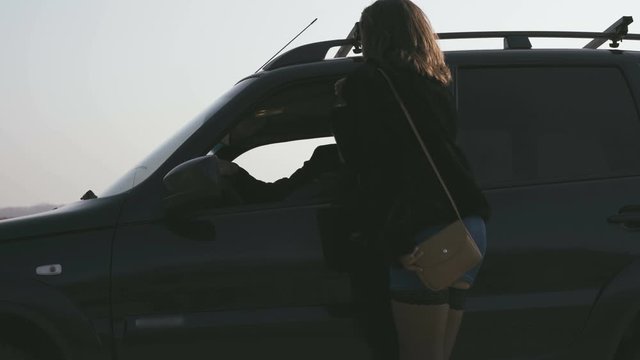 Female Prostitute Stands On The Road And Approaches The Client Car