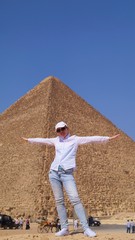  Fair-skinned girl in white clothes posing against the backdrop of a pyramid in the desert in Cairo