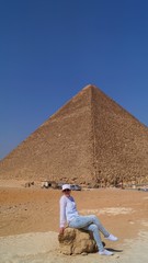  Fair-skinned girl in white clothes posing against the backdrop of a pyramid in the desert in Cairo