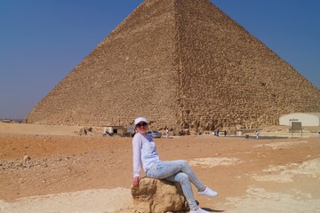  Fair-skinned girl in white clothes posing against the backdrop of a pyramid in the desert in Cairo