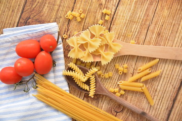 fantasia di pasta su cucchiai di legno e pomodori su tavolo cibo italiano