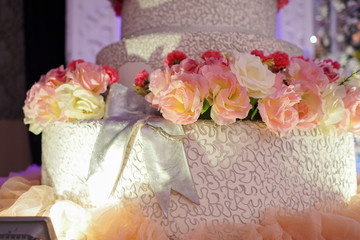 A four tiered wedding cake at the stage with flower