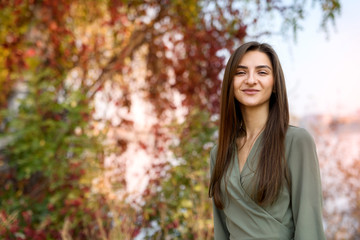 Naklejka premium Female portrait. Brunette woman portrait in autumn park wearing olive dress