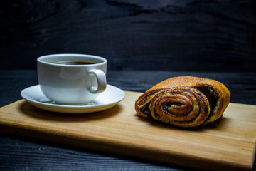 coffee with a mug next to a bun with poppy seeds. Selective focus