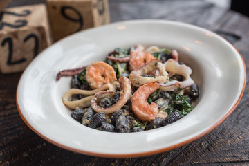 Black Conchiglie Pasta Shells with Seafood and Spinach. Modern Cafe Lunch.
