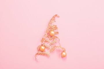 Christmas tree of painted golden leaves fern on pink paper background