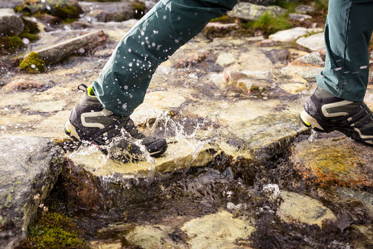 Rondane National Park, Norway: Detail of a male hiker crossing a alpine stream with his Adidas Core-Tex hiking boots.
