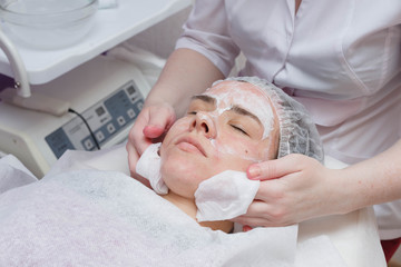 Beautician washes woman's face using cotton pads. Preparing for a cleaning face