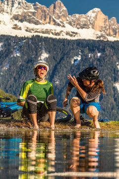 A female and male mountainbiker enjoying their time at a lake in South Tirol, Italy after a long ride in the alps.