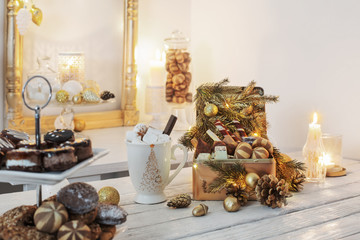 Christmas sweets in golden box and cocoa mug with marshmallows on a white table