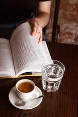Person with cup of coffee and book.
