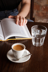 Person read a book while drinking coffee.