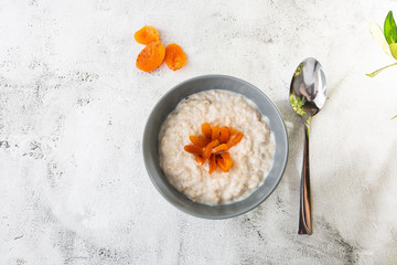 Oatmeal porridge or porridge oats or breakfast cereals with dried apricots isolated on white marble background. Homemade food. Tasty breakfast. Selective focus. Horizontal photo.