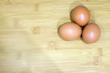 three chicken eggs on a background with a wood texture