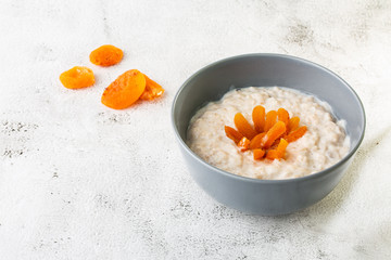 Oatmeal porridge or porridge oats or breakfast cereals with dried apricots isolated on white marble background. Homemade food. Tasty breakfast. Selective focus. Horizontal photo.