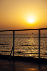 Colorful sunset in the Mediterranean sea with a cargo ship in a distance. View from the deck of a cruise ship