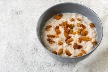 Oatmeal porridge or porridge oats or breakfast cereals with raisins isolated on white marble background. Homemade food. Tasty breakfast. Selective focus. Horizontal photo.