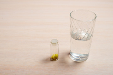 bottles with valerian tablets and a glass of water stand on a bright table