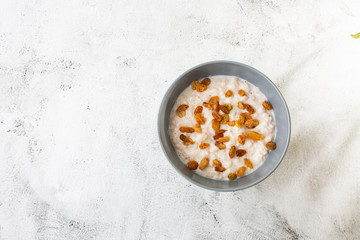 Fototapeta na wymiar Oatmeal porridge or porridge oats or breakfast cereals with raisins isolated on white marble background. Homemade food. Tasty breakfast. Selective focus. Horizontal photo.