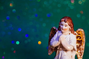 Porcelain angel on green bokeh background with copy space