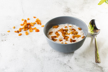 Oatmeal porridge or porridge oats or breakfast cereals with raisins isolated on white marble background. Homemade food. Tasty breakfast. Selective focus. Horizontal photo.