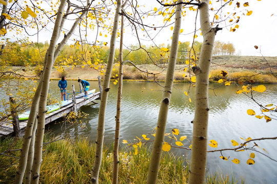 A man and a woman prepare their inflatable stand up paddle boards for SUPing in an alpine lake in the San Juan Mountains, Colorado in autumn.