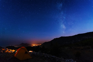 starry night with the Milky Way on the Turkish Mediterranean coast amidst the rocky mountains with tourists in a yellow tent