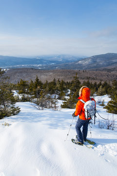 A woman takes in the dramatic vews of the Presidential Range and surrounding hills of the Mount Washington Valley while snowshoeing along Black Cap Mountain Trail near the summit of Black Cap Mountain in the Green Hills Preserve near North Conway, New Hampshire.